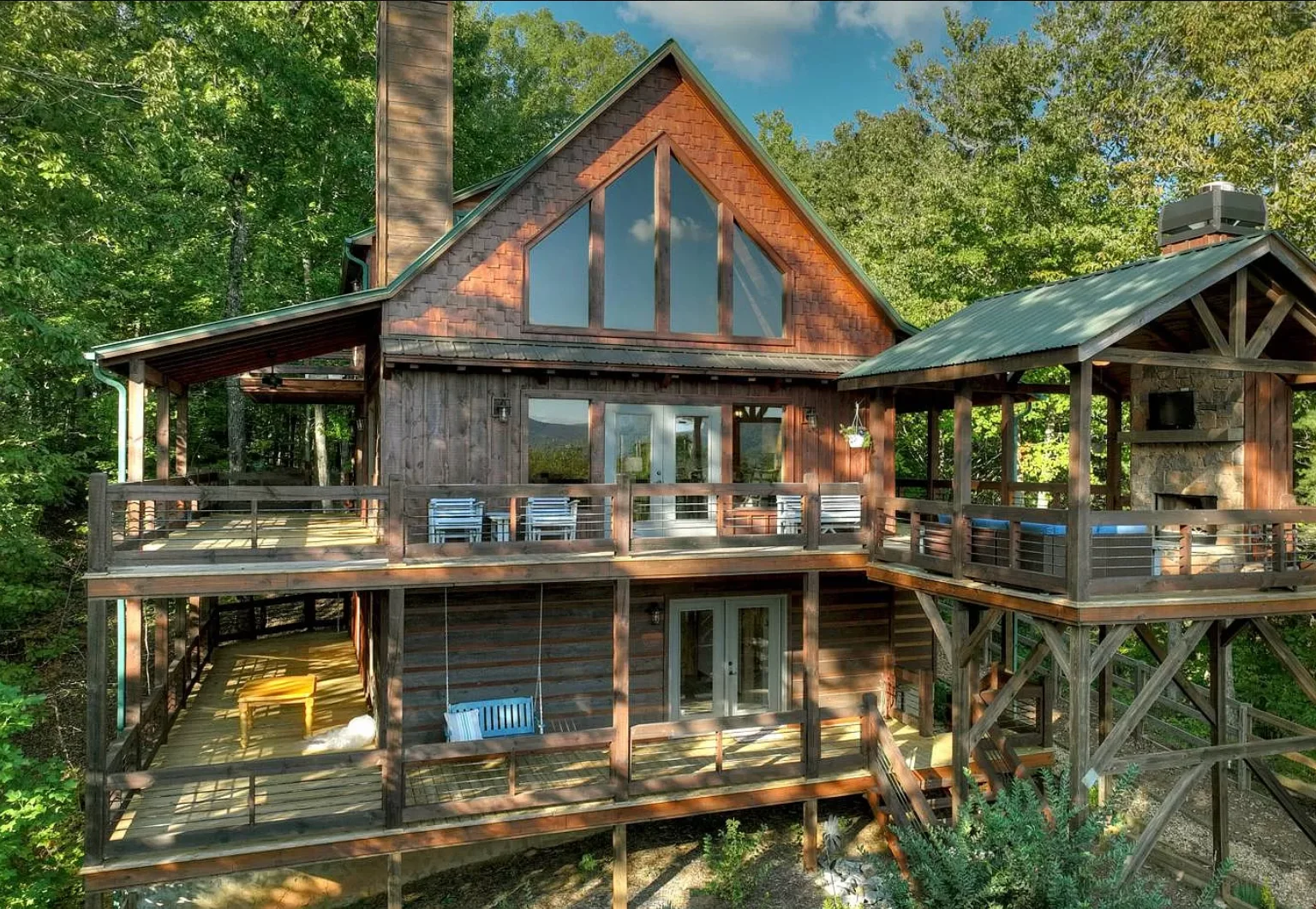 Rustic mountain chalet with wraparound decks and stone chimney surrounded by forest in Blue Ridge