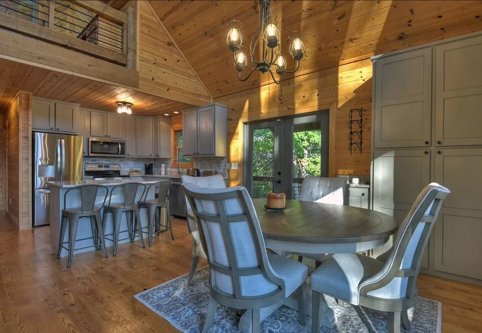 Family cabin dining room with round table, wooden ceiling beams and modern kitchen in Blue Ridge