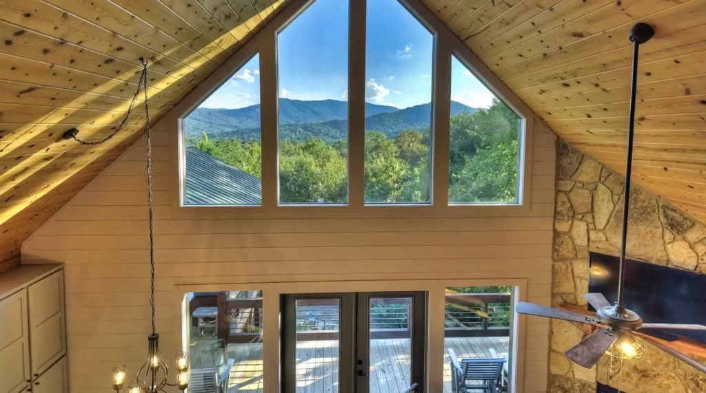 Modern A-frame chalet living room with vaulted wooden ceilings and mountain views through windows in Blue Ridge vacation