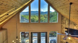 Modern A-frame chalet living room with vaulted wooden ceilings and mountain views through windows in Blue Ridge vacation