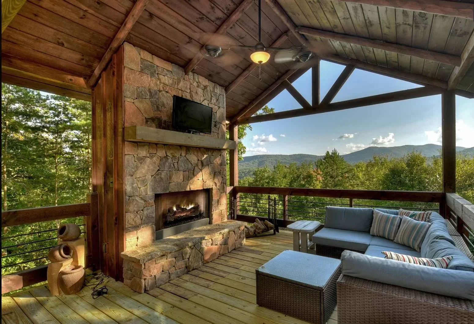 Elevated covered patio with stone fireplace and mountain views at Chalet Blue Ridge