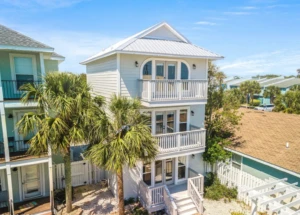 Modern beachfront vacation rental with white siding, balconies and palm trees in Panama City Beach FL