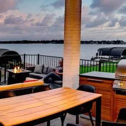 Elegant lakeside patio with dining table and fireplace at sunset in Montgomery