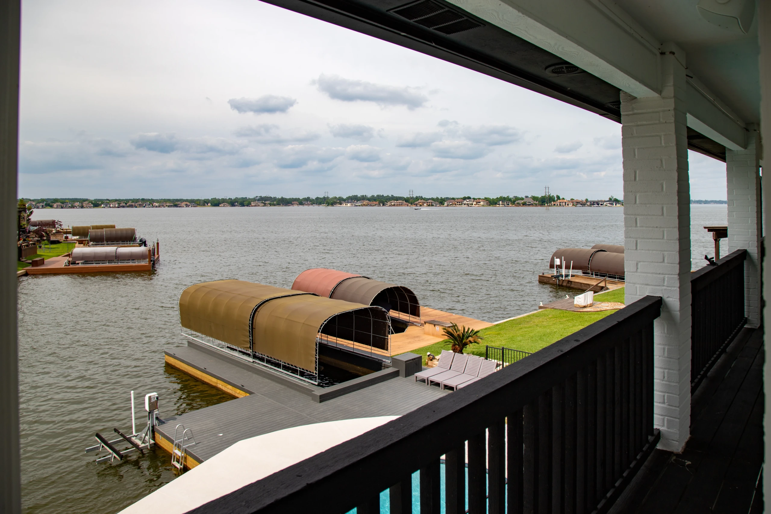 Private boat docks with covered boat lifts on a calm bay at The Waterfront Villa, a Lake Conroe summer pool and dock day in