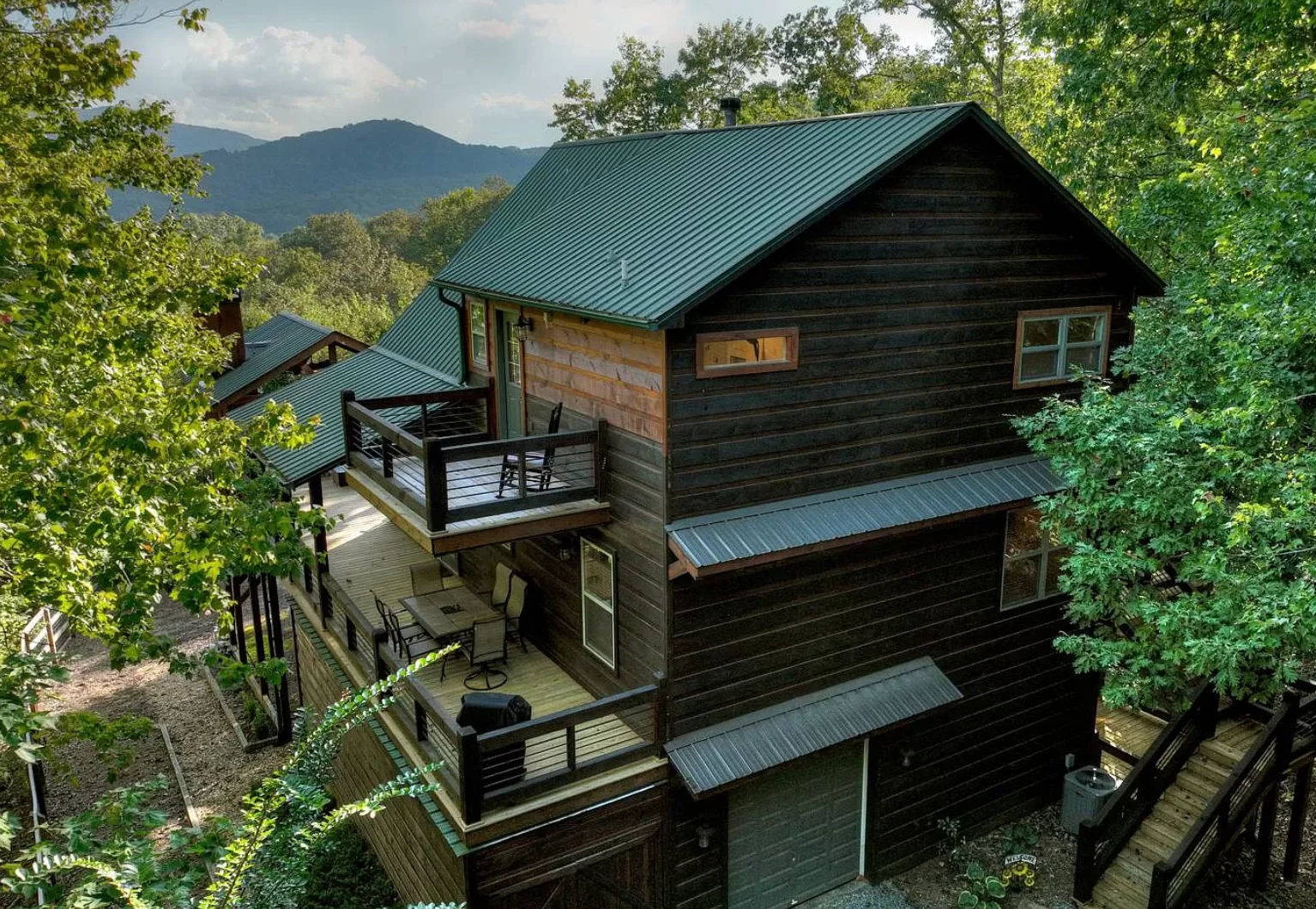 Modern mountain chalet exterior with dark wood siding, teal metal roof and elevated decks at a Blue Ridge, GA rental by Nest
