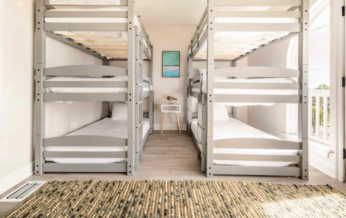 Bright dormitory-style bedroom with four built-in bunk beds, white bedding, and a striped rug at Sea La Vie in Panama City