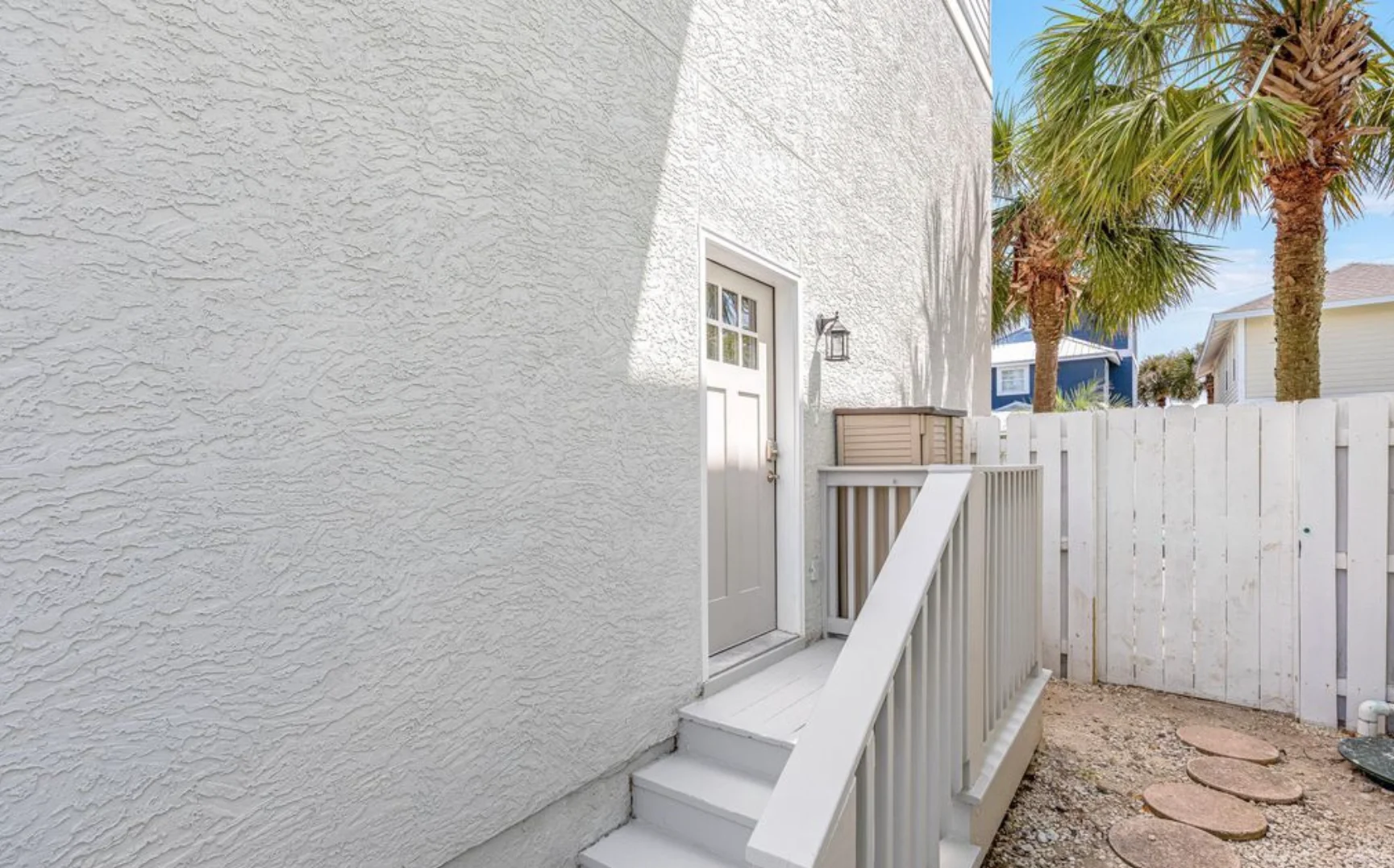 White stucco coastal home exterior with palm trees at Panama City Beach rental property