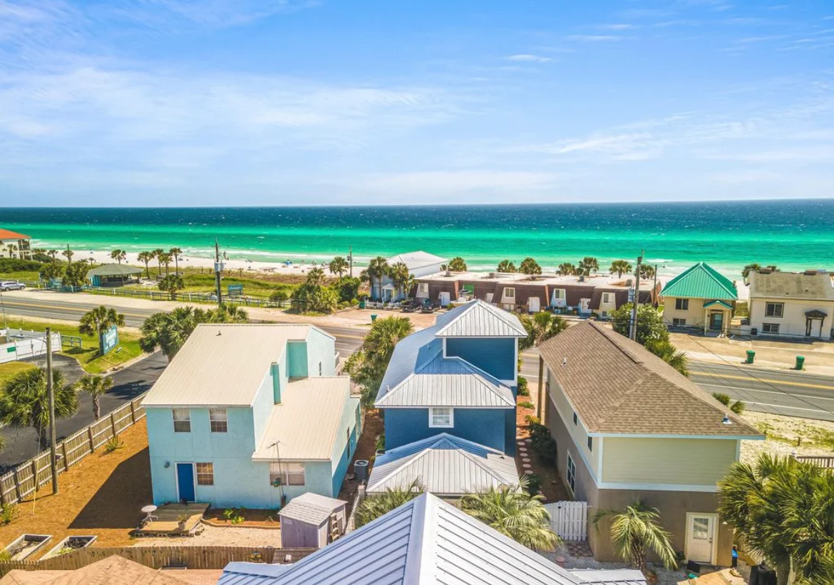 Aerial view of colorful beach homes with metal roofs by turquoise water in a Panama City Beach, FL coastal community at Sea