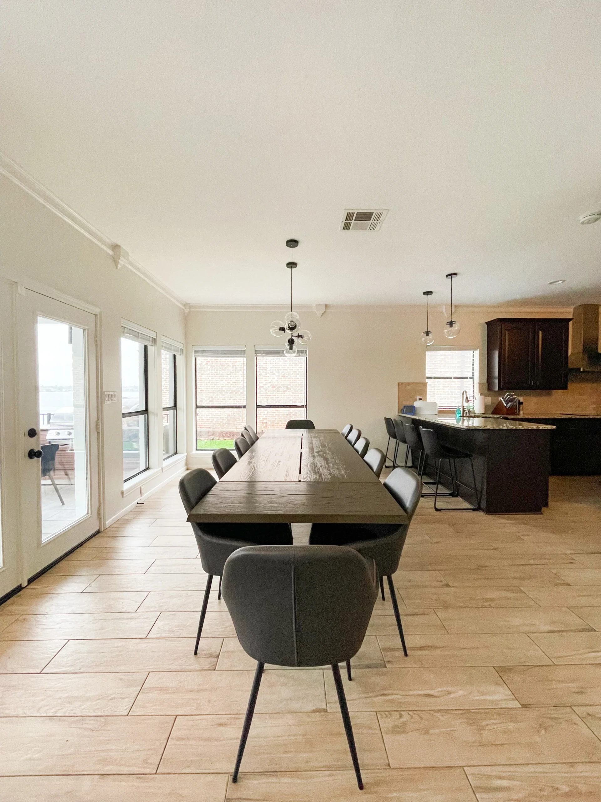 Open-concept dining room with wooden table, gray chairs, and granite kitchen in a waterfront villa, Montgomery TX Nest Awaits