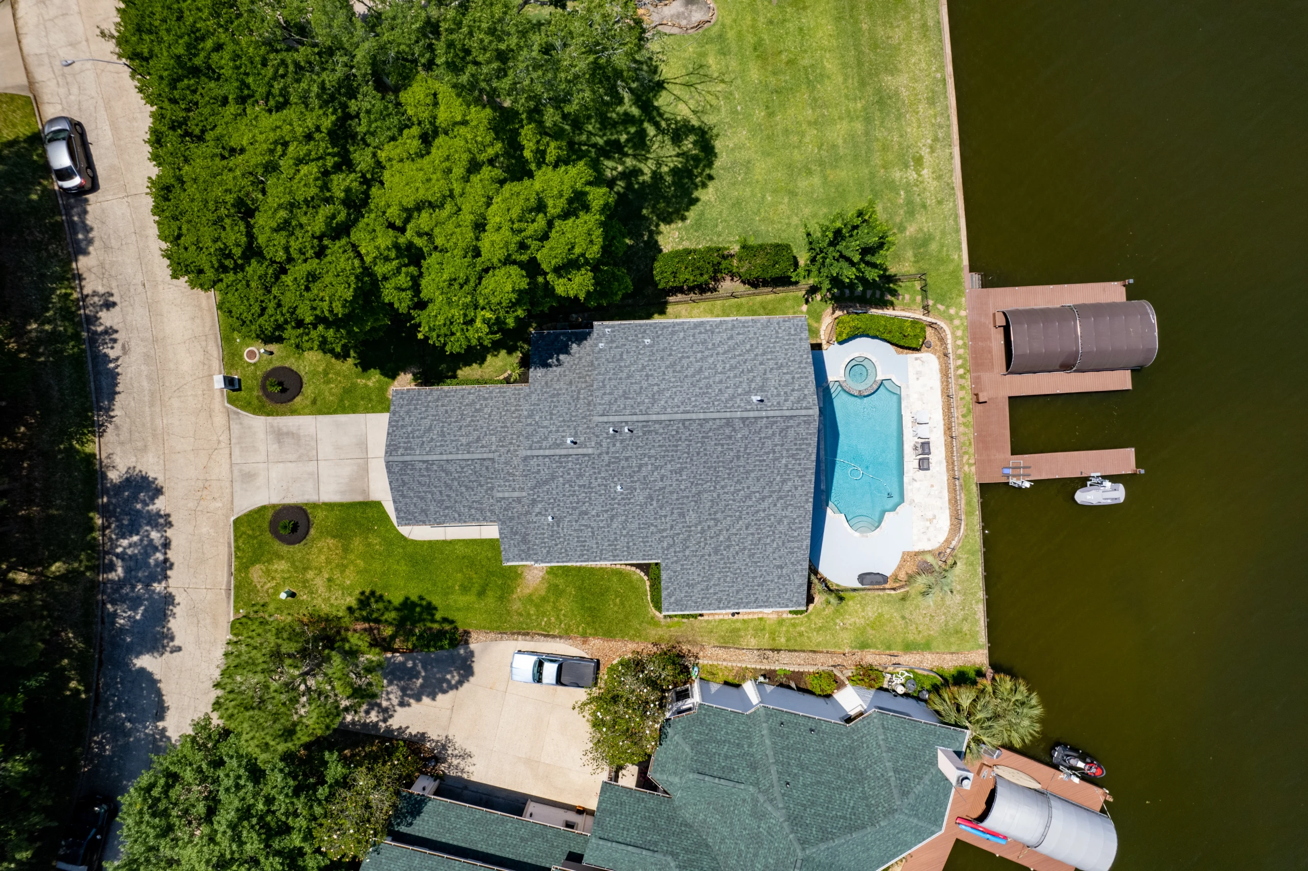 Aerial view of a lakefront home with pool and private dock, a Nest Awaits stay for planning trips beyond the Parkway