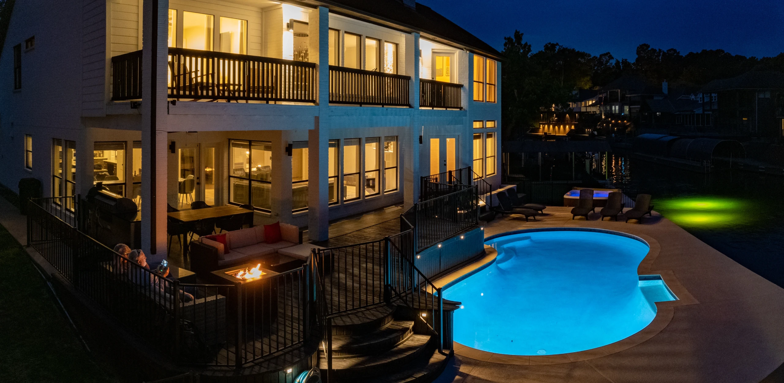 Waterfront villa with pool and fire pit at dusk for a weekend trip with friends