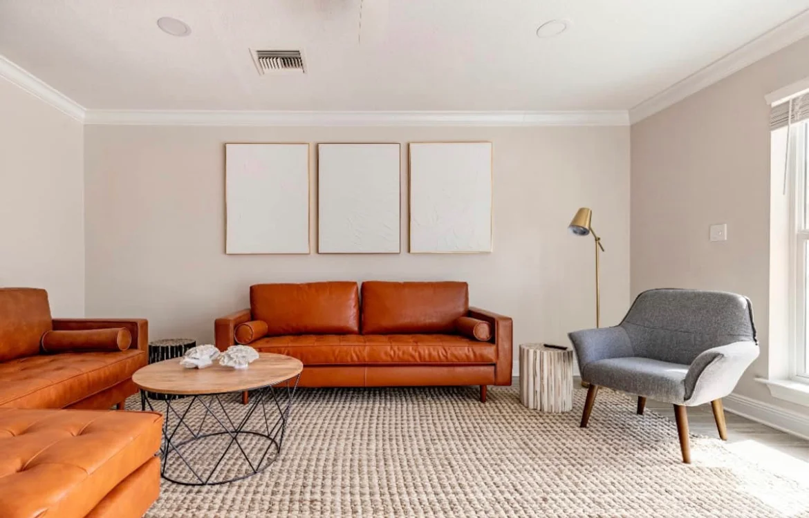 Modern living room with burnt orange leather sofa and round wooden table at Panama City Beach vacation rental