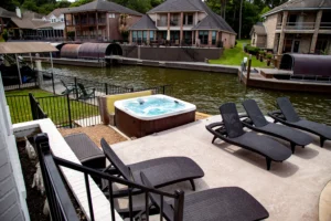 Waterfront patio with hot tub and lounge chairs on a concrete deck overlooking a calm canal, a 3 bedroom house option in
