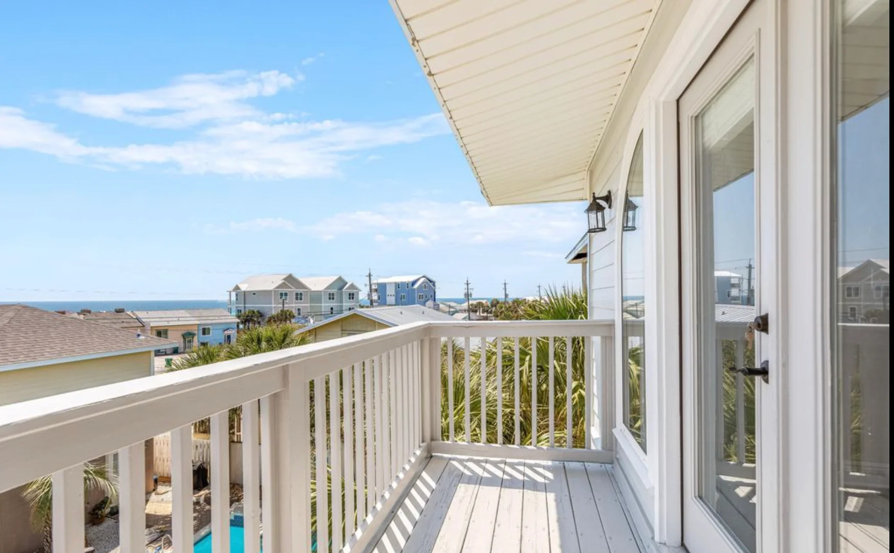 Oceanfront deck with white railings and retractable awning overlooking Atlantic beach views in Panama City Beach, FL, Sea La