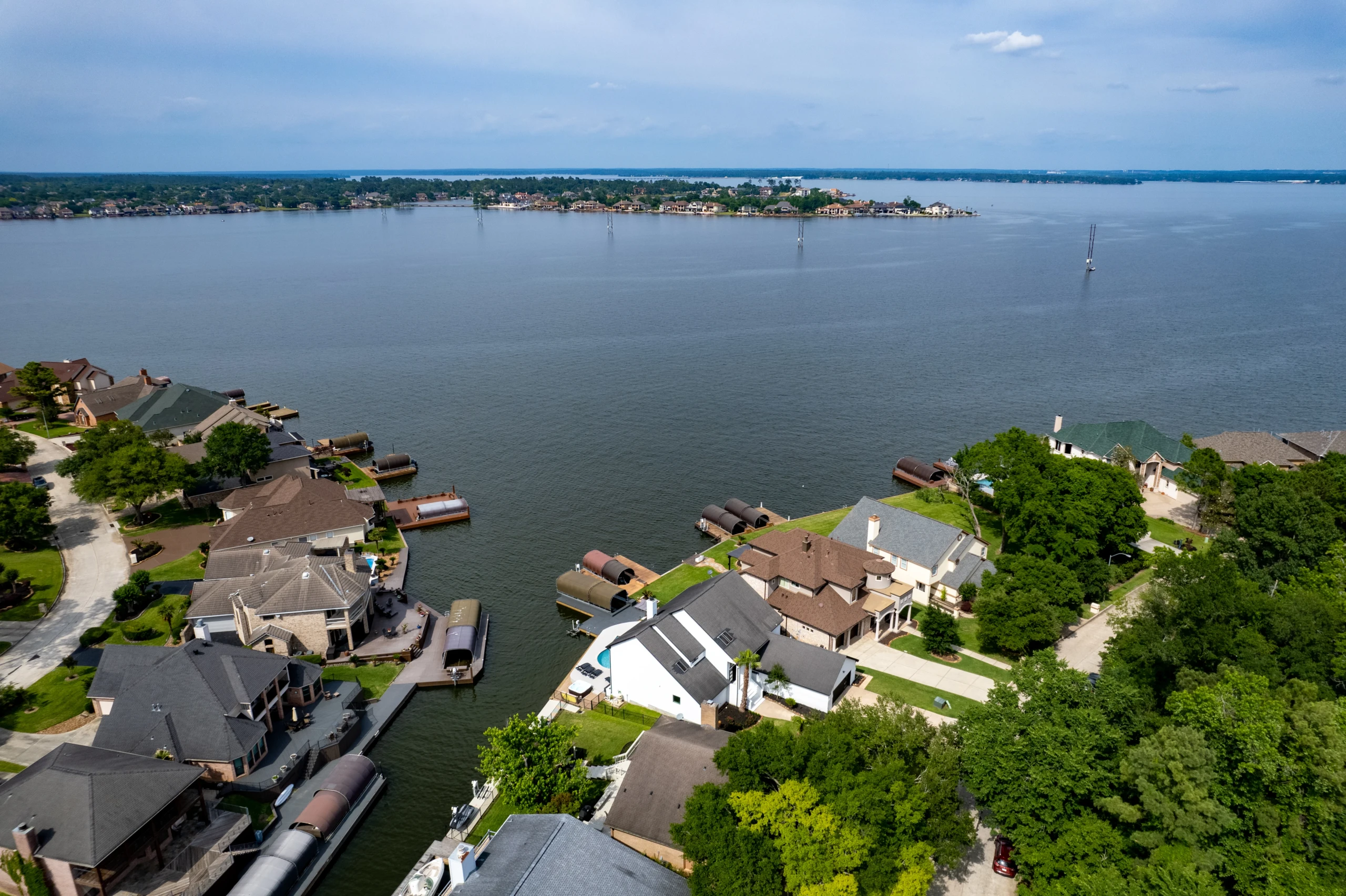 Aerial view of luxury lake homes with private docks and sailboats on calm water, a waterfront living retreat in Montgomery,